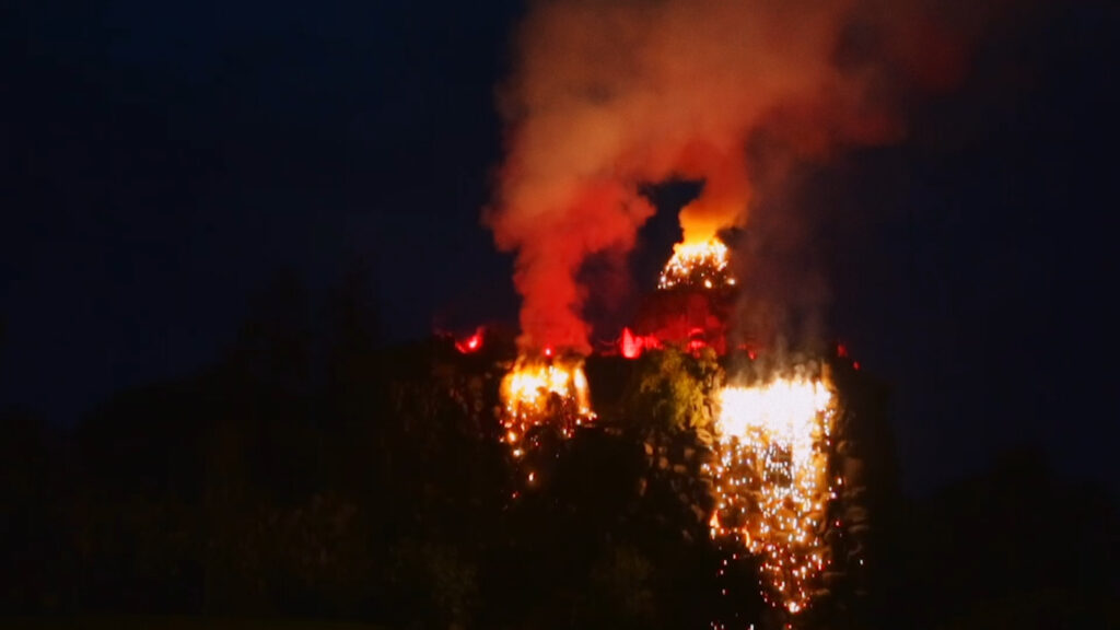 An explosion of smoke and lights in the darkness with a waterfall of fire from an artificial volcano.